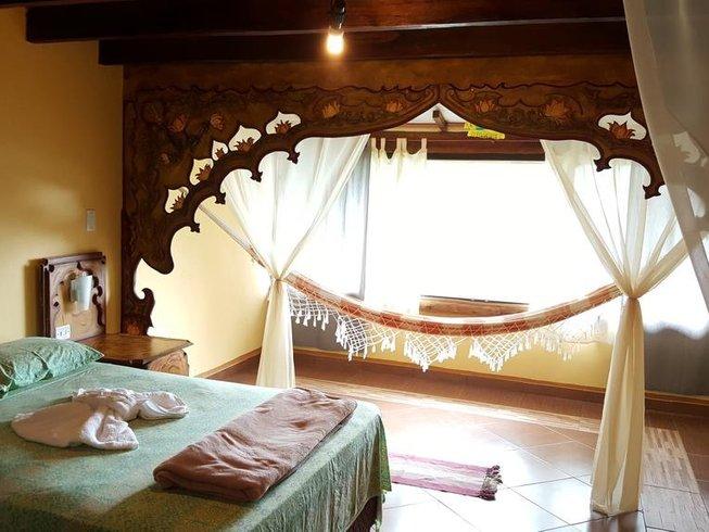Quarto com rede na janela, arco de madeira entalhada e cama preparada